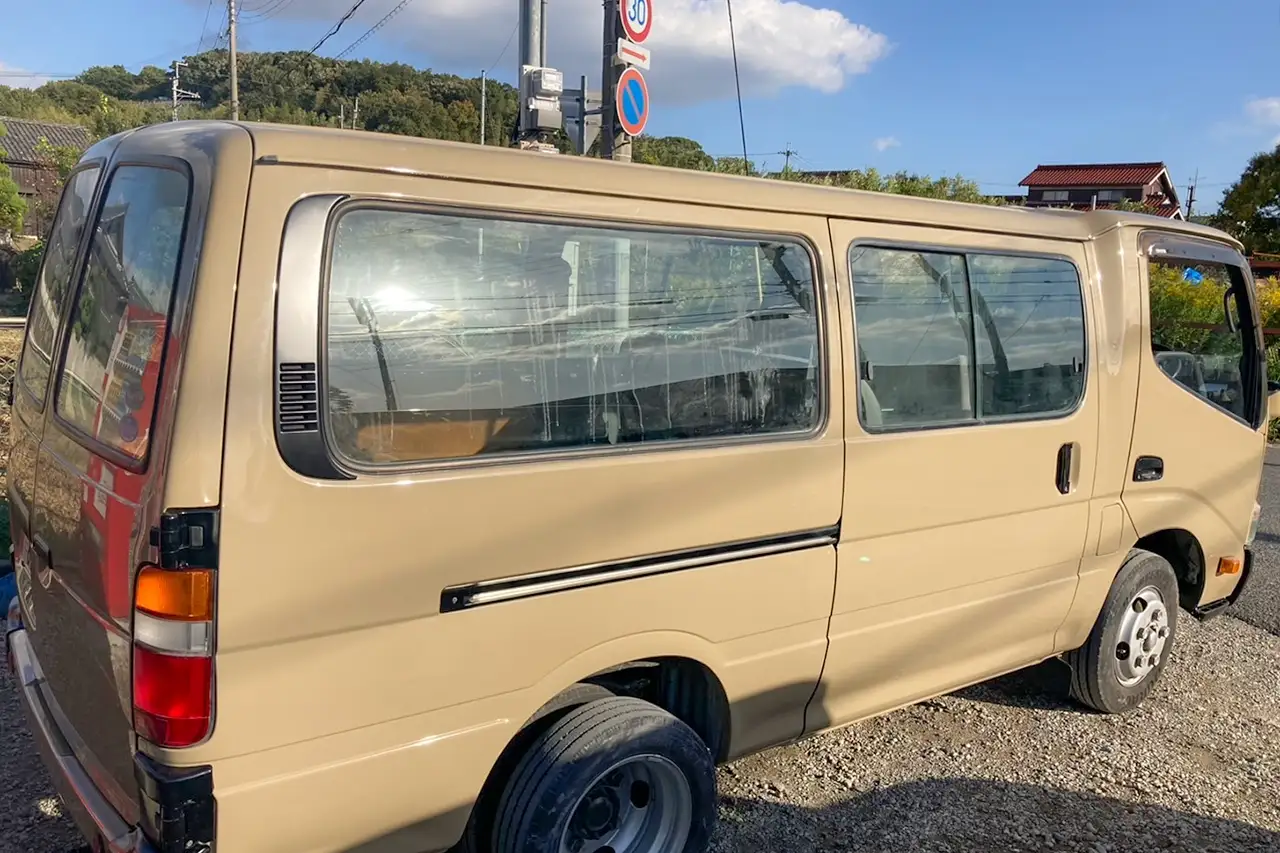 屋外に停められたベージュのカスタムバン